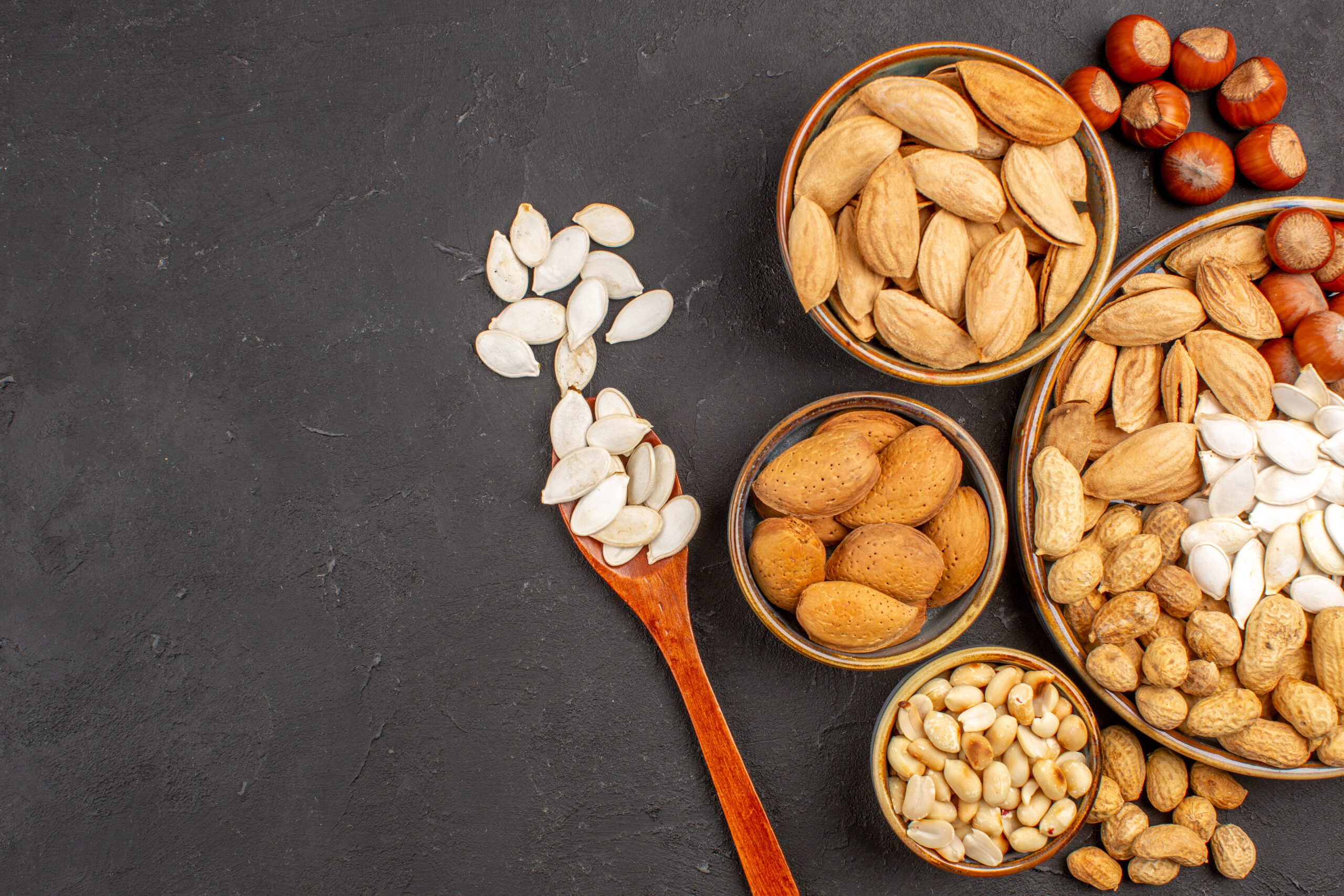 top-view-different-nuts-fresh-nuts-inside-pots-dark-surface